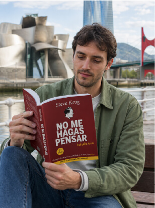 Chico leyendo el libro No me hagas pensar de Steve Krug junto a la ría de Bilbao
