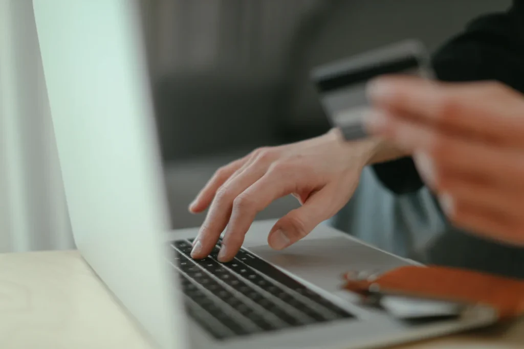 Persona utilizando una tarjeta de crédito y un portátil para realizar una compra online y representar el checkout ecommerce