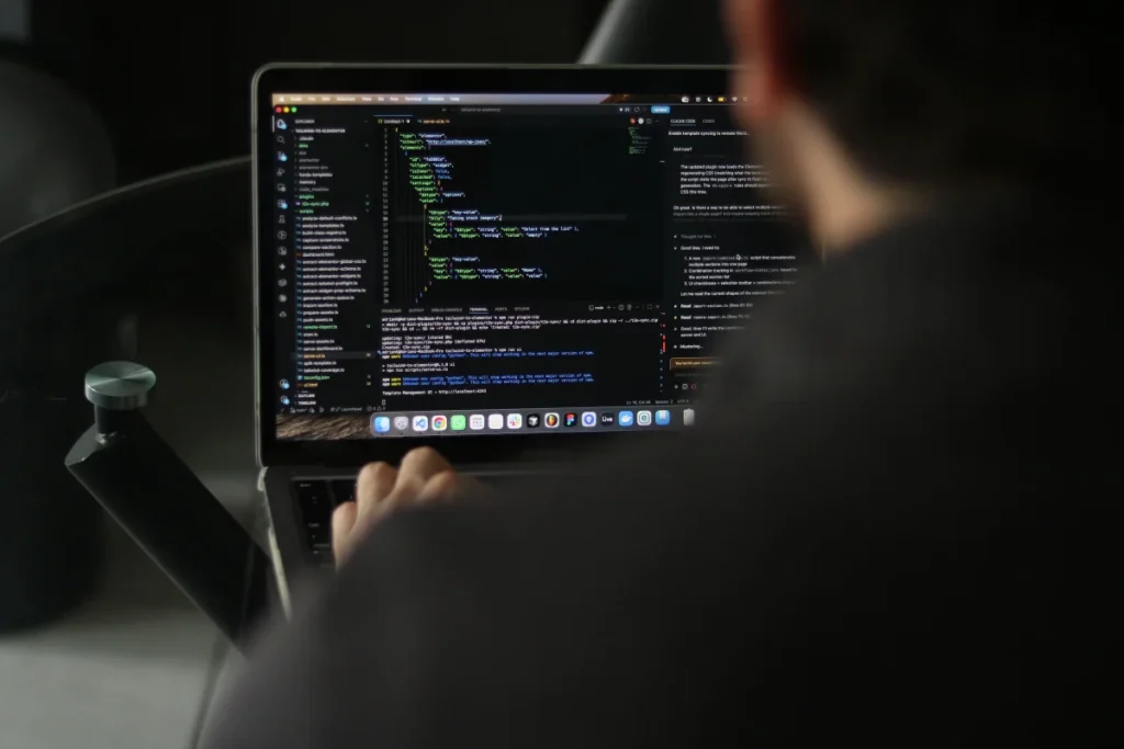 Desarrollador trabajando con código en un portátil para ilustrar un flujo de vibe coding asistido por inteligencia artificial