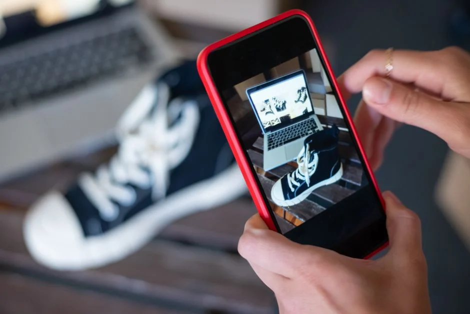 Persona fotografiando unas zapatillas con un móvil para ilustrar la creación de fichas de producto en WooCommerce