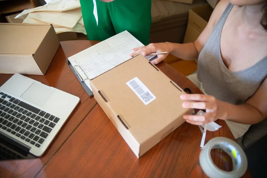 Pequeño negocio preparando pedidos junto a un portátil para ilustrar la gestión de envíos en WooCommerce